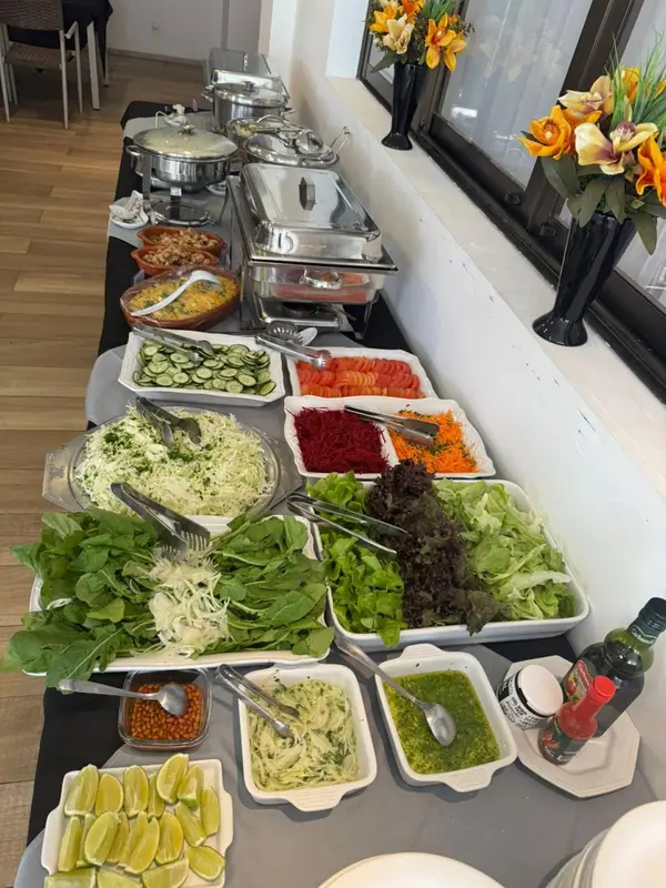 Saladas e legumes em buffet com arranjo de flores laranja