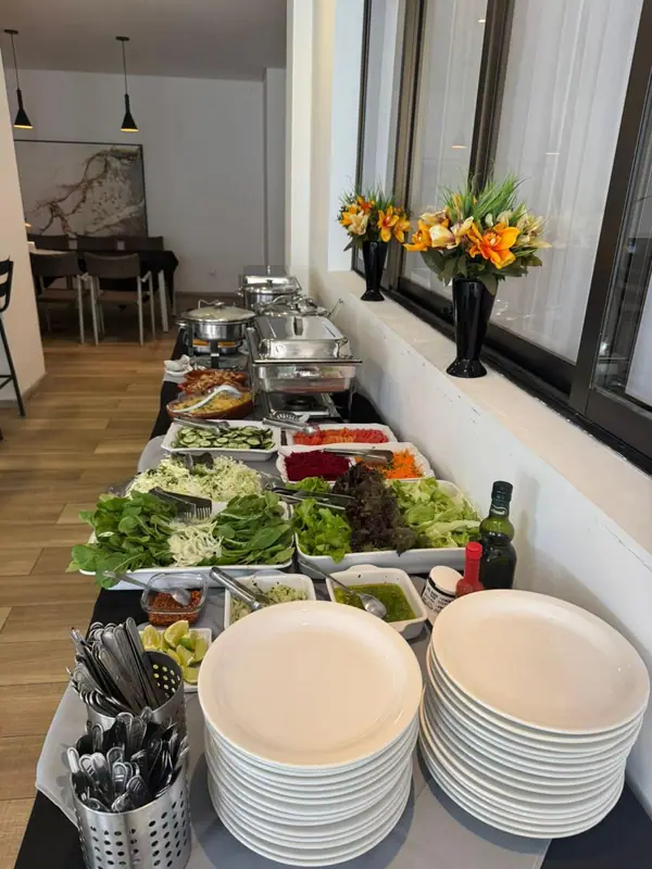 Buffet montado com saladas e pilhas de pratos