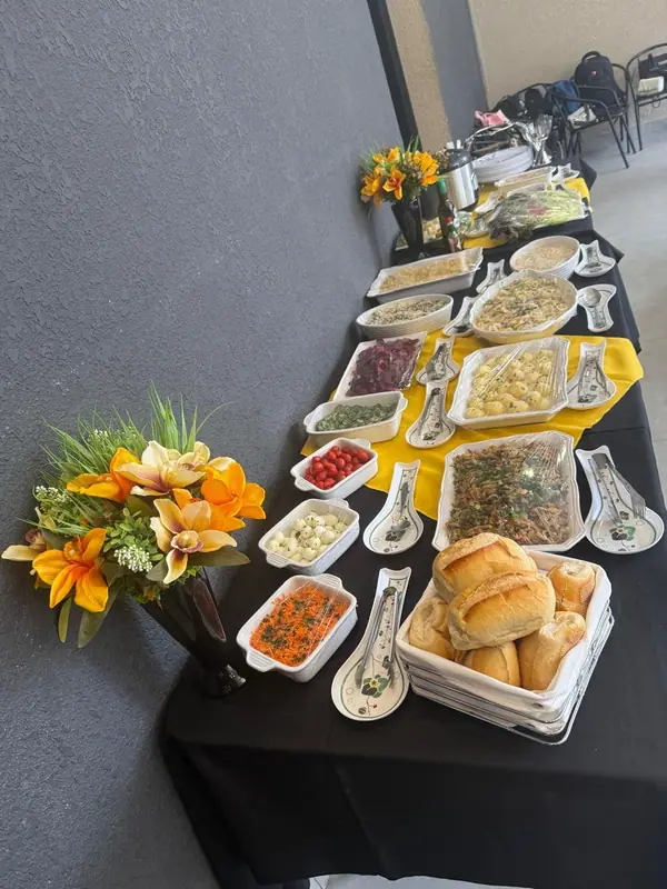 Mesa de buffet com saladas, pães e arranjo de flores
