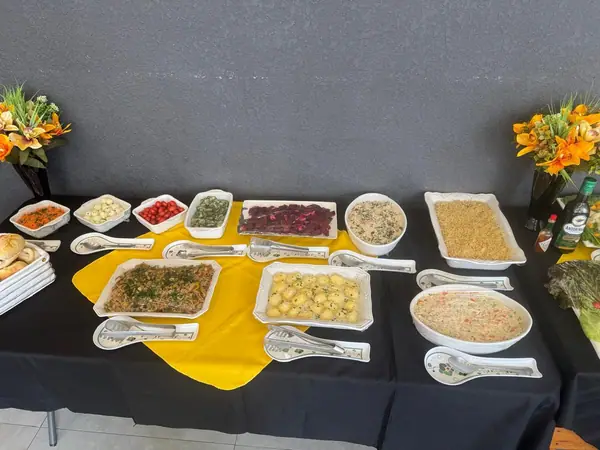 Mesa de buffet com saladas e petiscos sobre toalha amarela