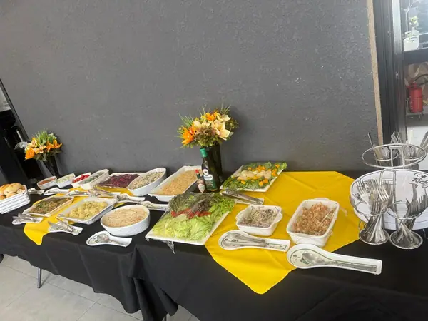 Buffet com travessas e arranjo de flores sobre toalha amarela