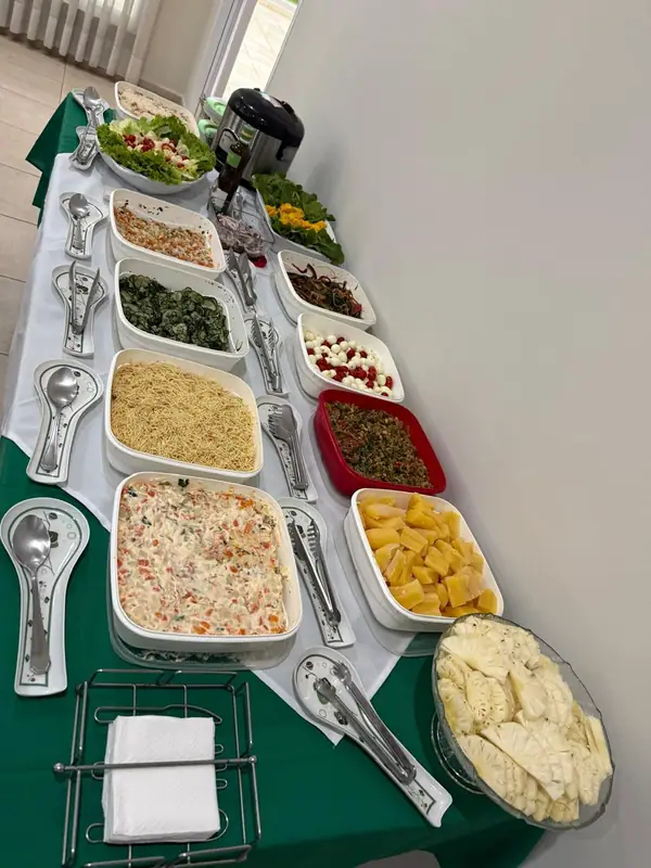 Fileira de saladas e guarnições em mesa com toalha verde