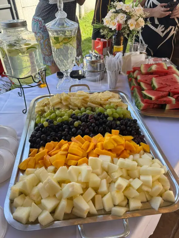 Travessa de frutas e queijos ao lado de jarras de suco