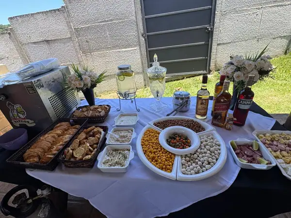 Mesa de petiscos e jarras de bebida sobre toalha branca