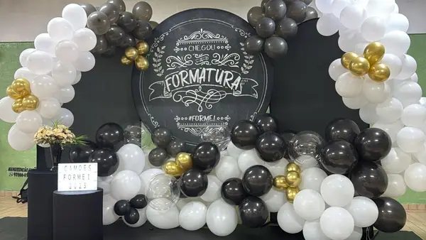 Painel de formatura com balões brancos, pretos e dourados