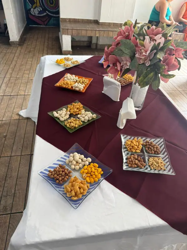 Mesa de petiscos com arranjo de flores e passadeira bordô