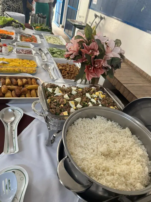 Buffet com arroz, carnes e saladas ao lado de flores