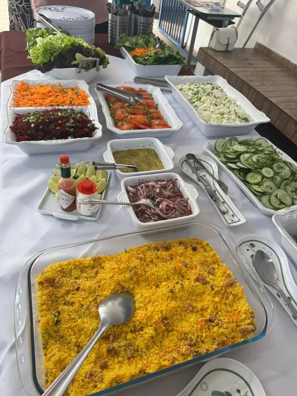 Farofa e saladas em mesa com toalha branca