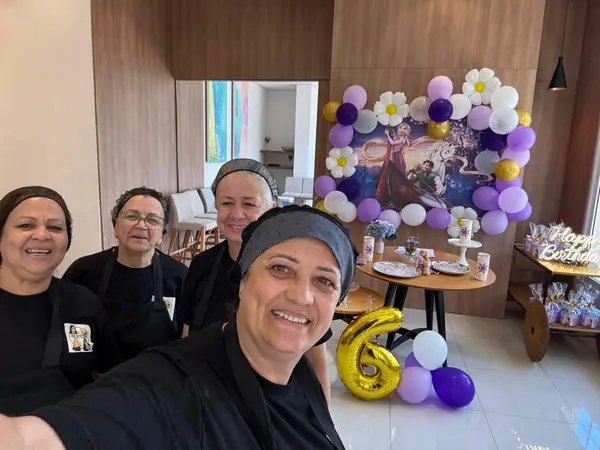 Equipe em selfie diante da decoração de aniversário de seis anos