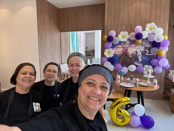 Equipe em selfie diante da decoração de aniversário de seis anos