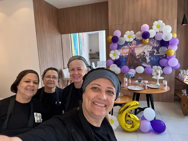 Equipe em selfie diante da decoração de aniversário de seis anos