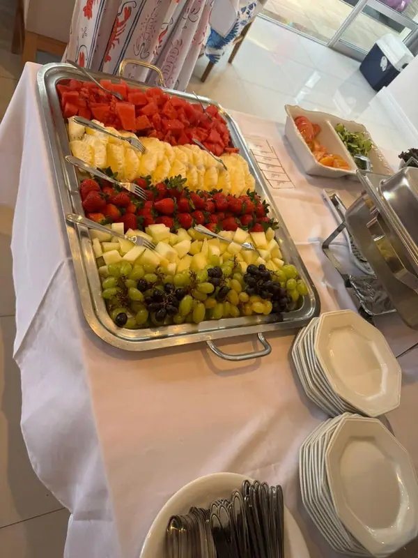 Travessa de frutas em mesa branca com pratos empilhados