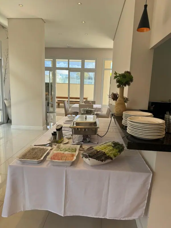 Mesa de buffet com pratos empilhados em salão claro