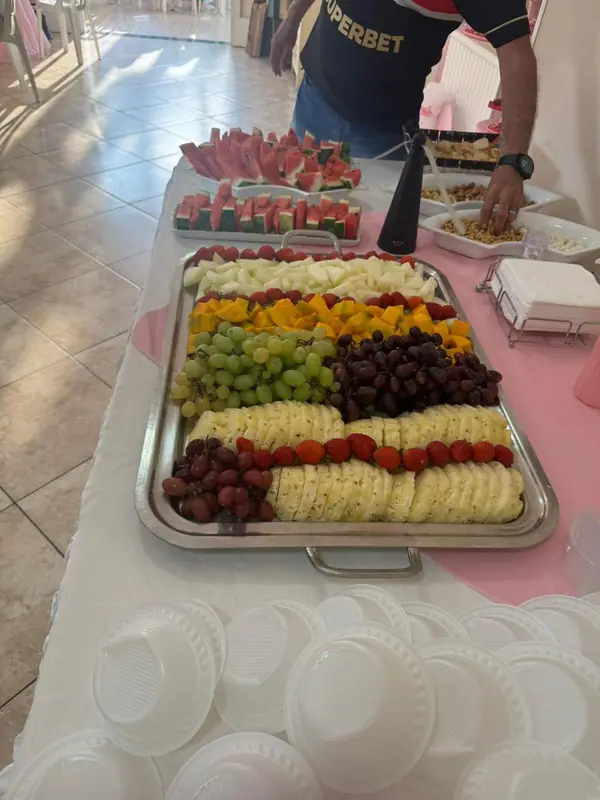 Travessa de frutas e queijos sobre toalha rosa