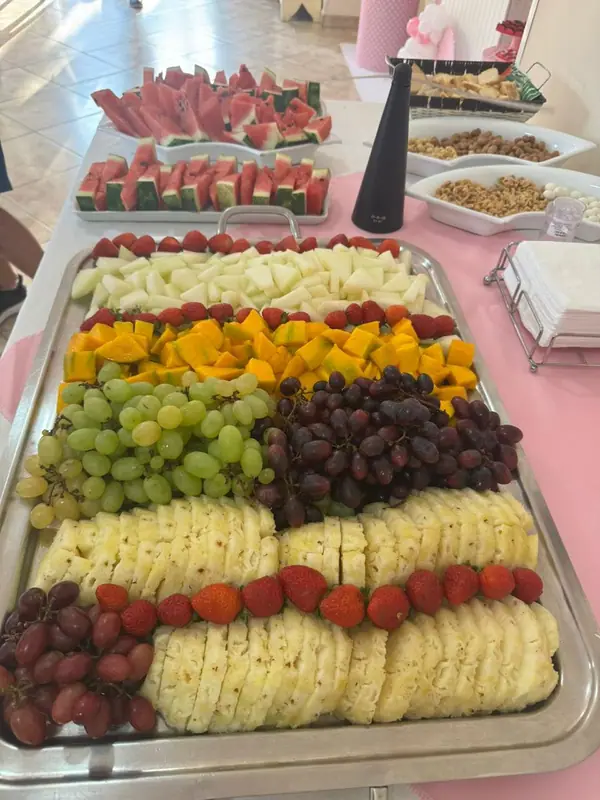 Travessa de frutas e queijos sobre toalha rosa