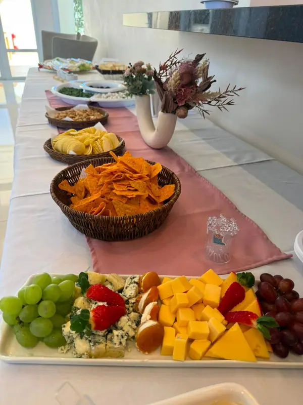 Buffet com passadeira rosa, frutas e petiscos